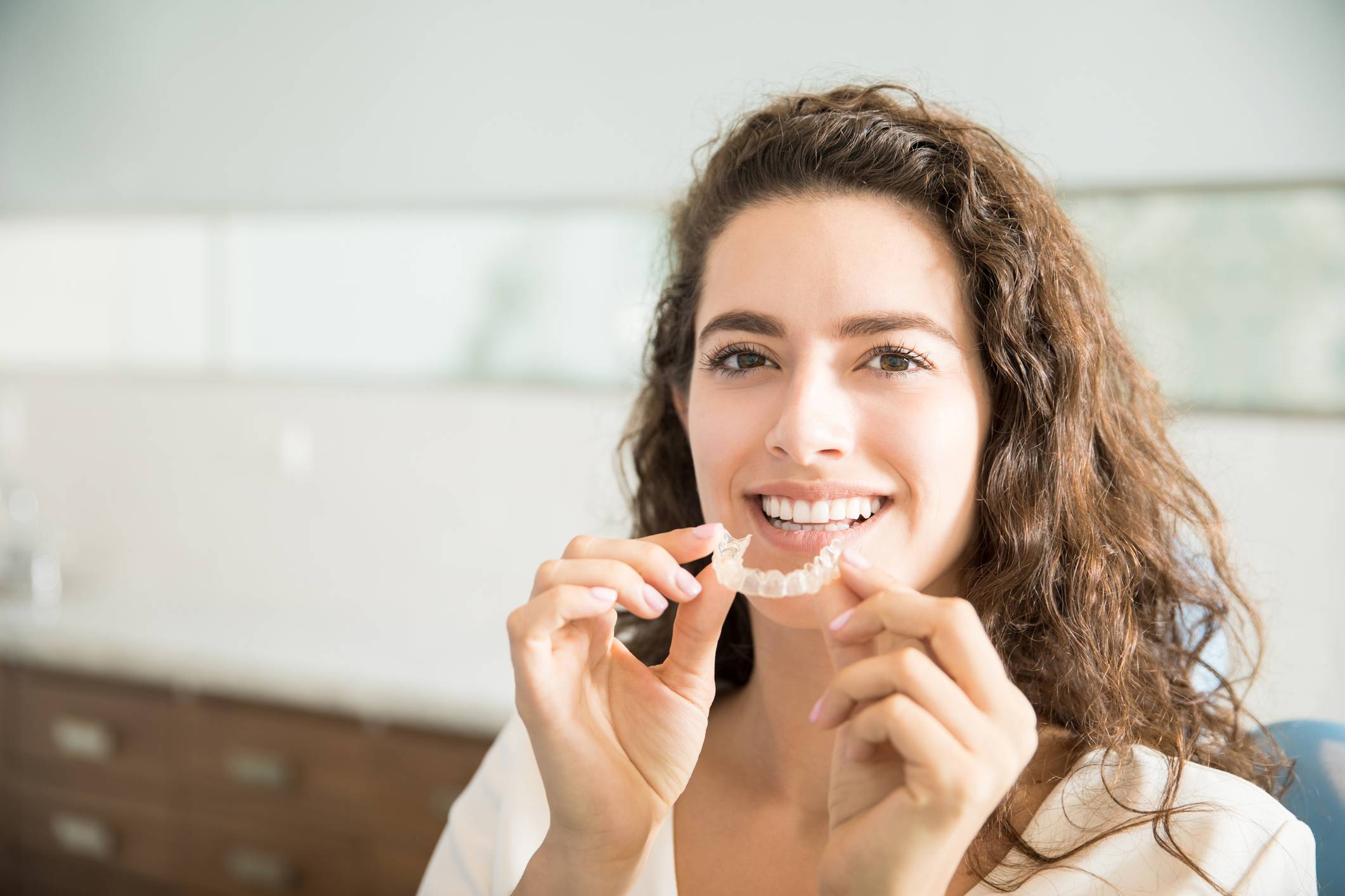 Uśmiechnięta kobieta trzymająca nakładkę na zęby